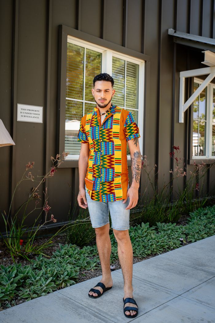 Home Man in vibrant shirt posing outside a stylish building in summer.