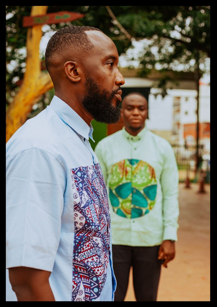 Home Adult serious hipster black man in ornamental shirt with African pattern against friend in town on summer day
